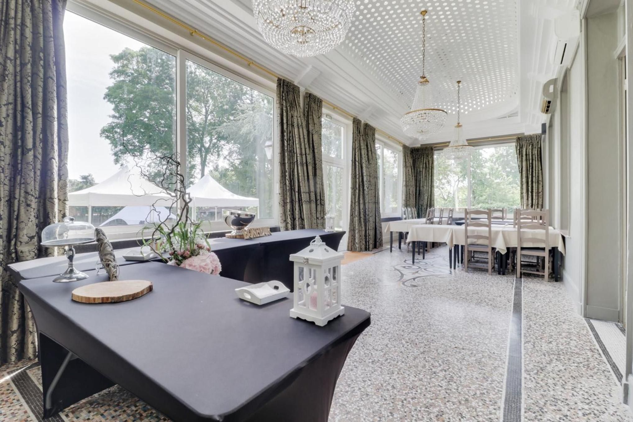 Un comedor amplio con una mesa larga dispuesta para varios comensales, ventanas grandes con cortinas y un candelabro.