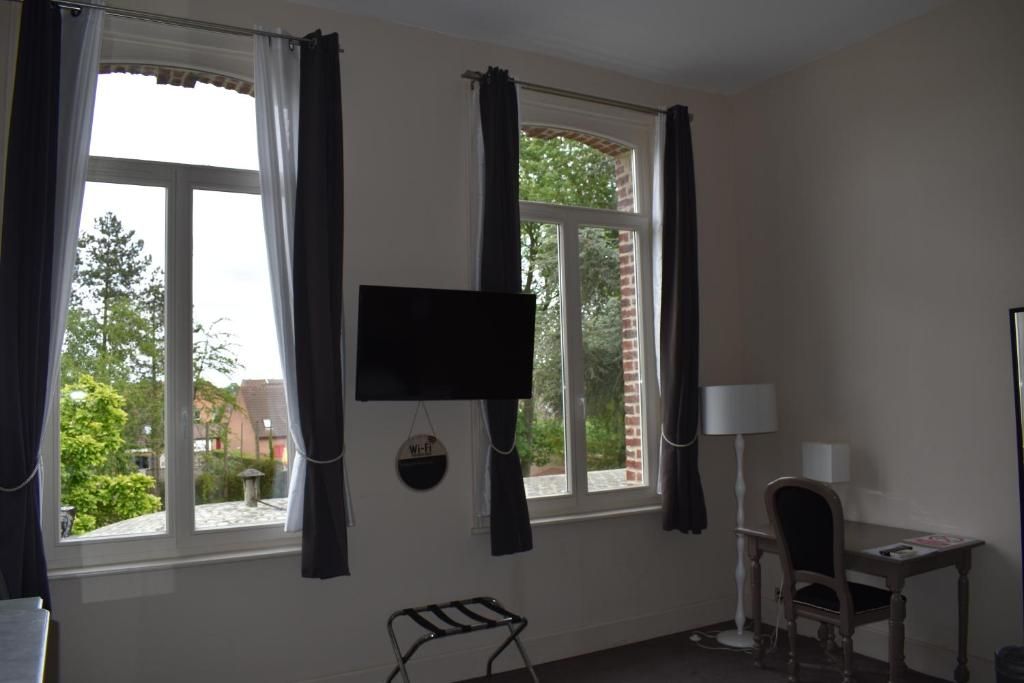 A room with a desk, chair, and a flat-screen TV mounted on the wall.