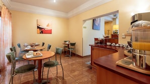 A hotel dining area with a bar, breakfast setup, and a painting on the wall. - Hotel de Bordeaux (Clermont-Ferrand)