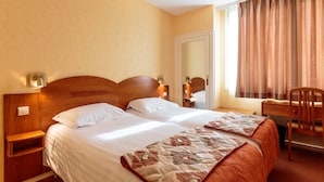 A double bed with a wooden headboard, two bedside tables, a desk with a chair, and a large mirror. - Hotel de Bordeaux (Clermont-Ferrand)