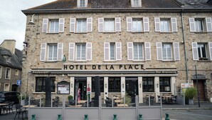 A two-story building with a sign reading "HOTEL DE LA PLACE." - Hotel De la Place (Les Monts d'Aunay)