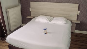 A neatly made bed with white linens, a wooden headboard, and two wall-mounted mirrors.