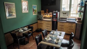 Un restaurant avec une longue table, des chaises et un comptoir où se trouve une machine à café.