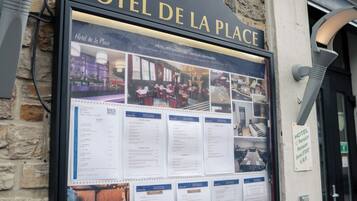 Ein Schild für das HOTEL DE LA PLACE mit Informationen zu Zimmern und Annehmlichkeiten.