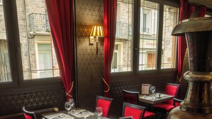 A restaurant interior with red velvet chairs, a large metal vase, and a tiled floor. - Hotel De la Place (Les Monts d'Aunay)