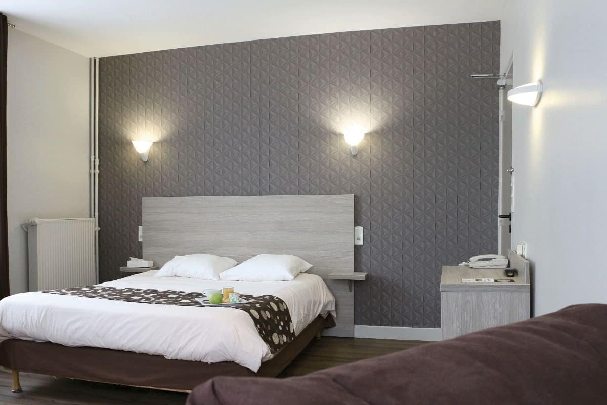 Ein modernes Hotelzimmer mit einem großen Bett, zwei Nachttischlampen, einem Nachttisch mit Telefon und einem Heizkörper.