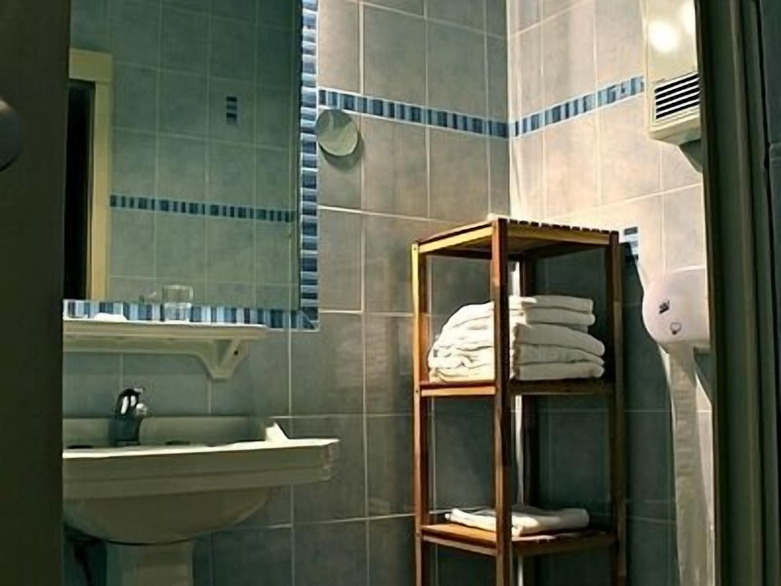 A bathroom with a sink, mirror, and a towel rack.