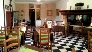Un'area pranzo con pavimento a scacchi, sedie di legno e tavoli apparecchiati.
