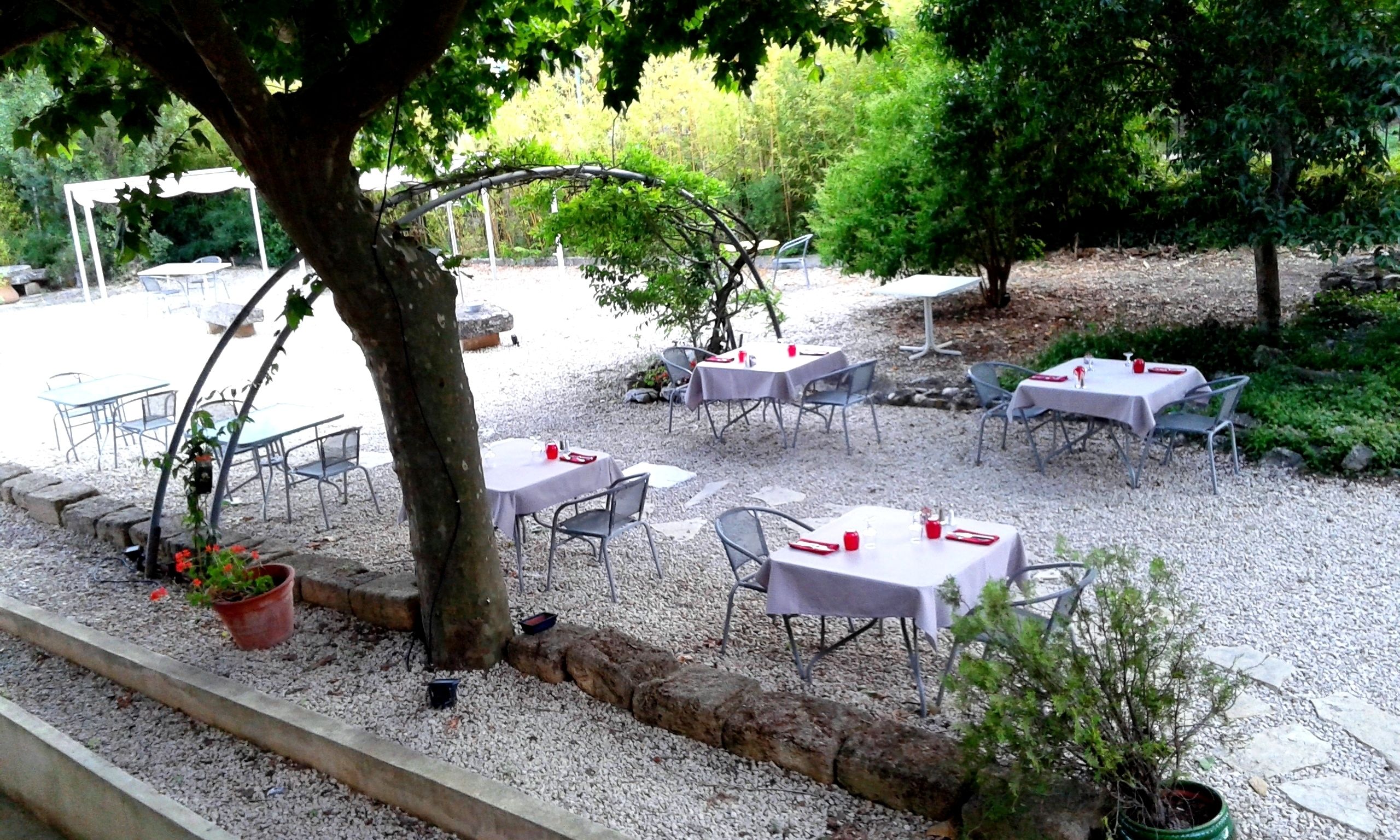 An outdoor patio area with tables and chairs, surrounded by gravel and greenery.