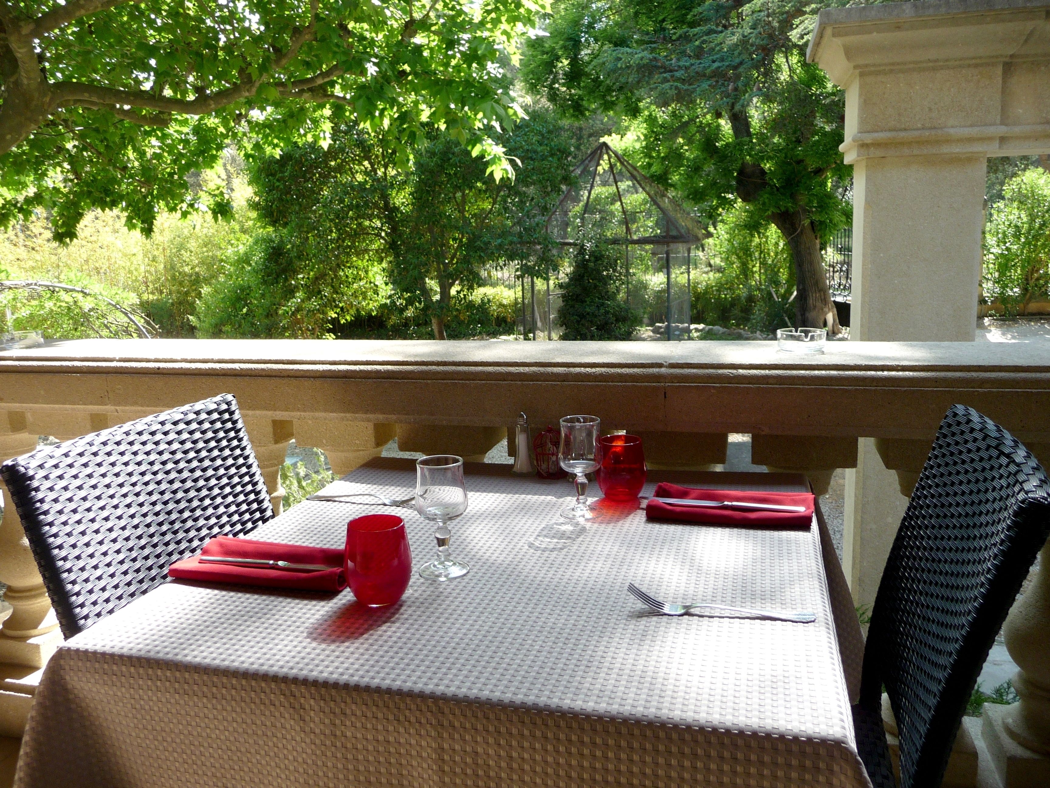 Mesa dispuesta para dos con vista a un jardín.