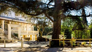 Un edificio storico con un balcone, una scala e un'area giardino con struttura in vetro.