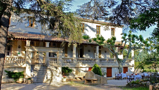 Un edificio a due piani con un balcone, una scala e posti a sedere all'aperto.
