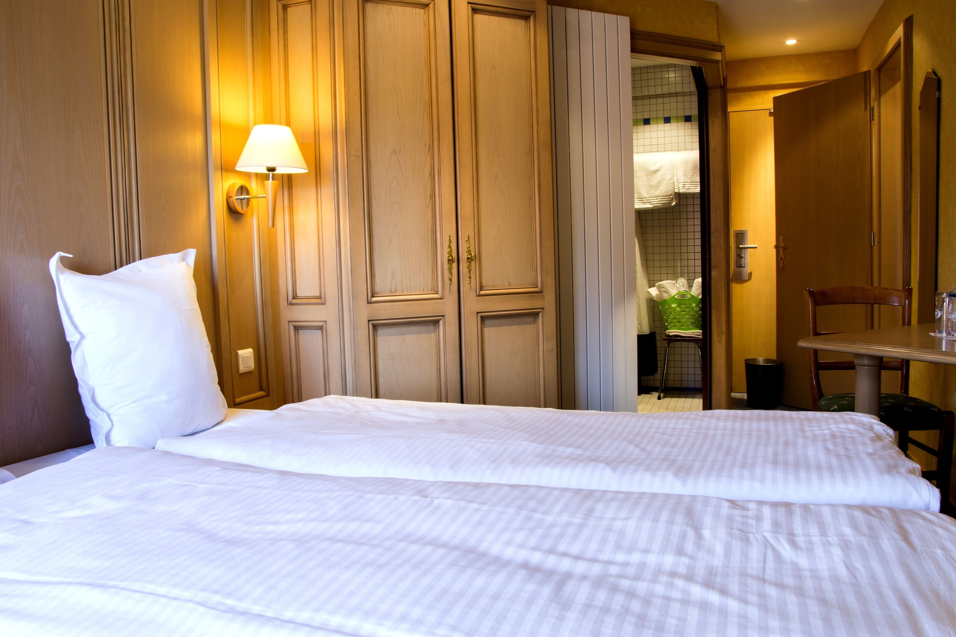 A hotel room with a large bed, a desk, and a chair.