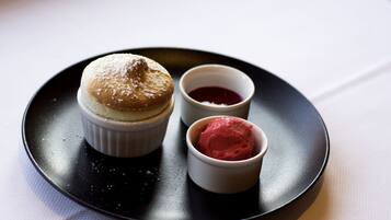 Un plato de postre con un pastel y dos recipientes pequeños de salsa roja.