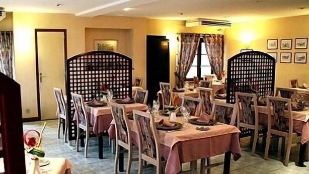 Un comedor con mesas dispuestas para comer, sillas y un separador decorativo.
