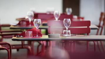 Un comedor con mesas dispuestas para dos, cada una con una copa de vino y un plato pequeño.