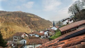 Un pueblo con arquitectura tradicional, una iglesia y una colina al fondo.