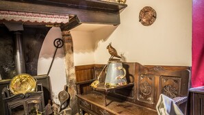 Una habitación tradicional con vigas de madera a la vista, una chimenea y una mesa dispuesta para comer.