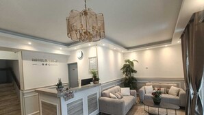 A hotel lobby with a reception desk, sofas, a coffee table, and a large plant. - Hôtel du Parc (Aulnay-sous-Bois)