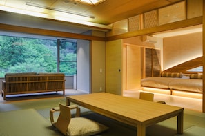 A traditional Japanese-style room with tatami flooring, a low table, a cushioned bench, and a bed with a wooden headboard.