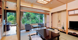 A modern hotel room with a balcony, a dining area, and a TV.