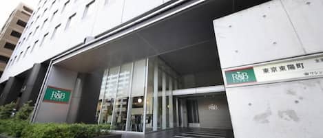 A hotel entrance with a modern design, featuring a glass facade and a signboard for R&B Hotel.