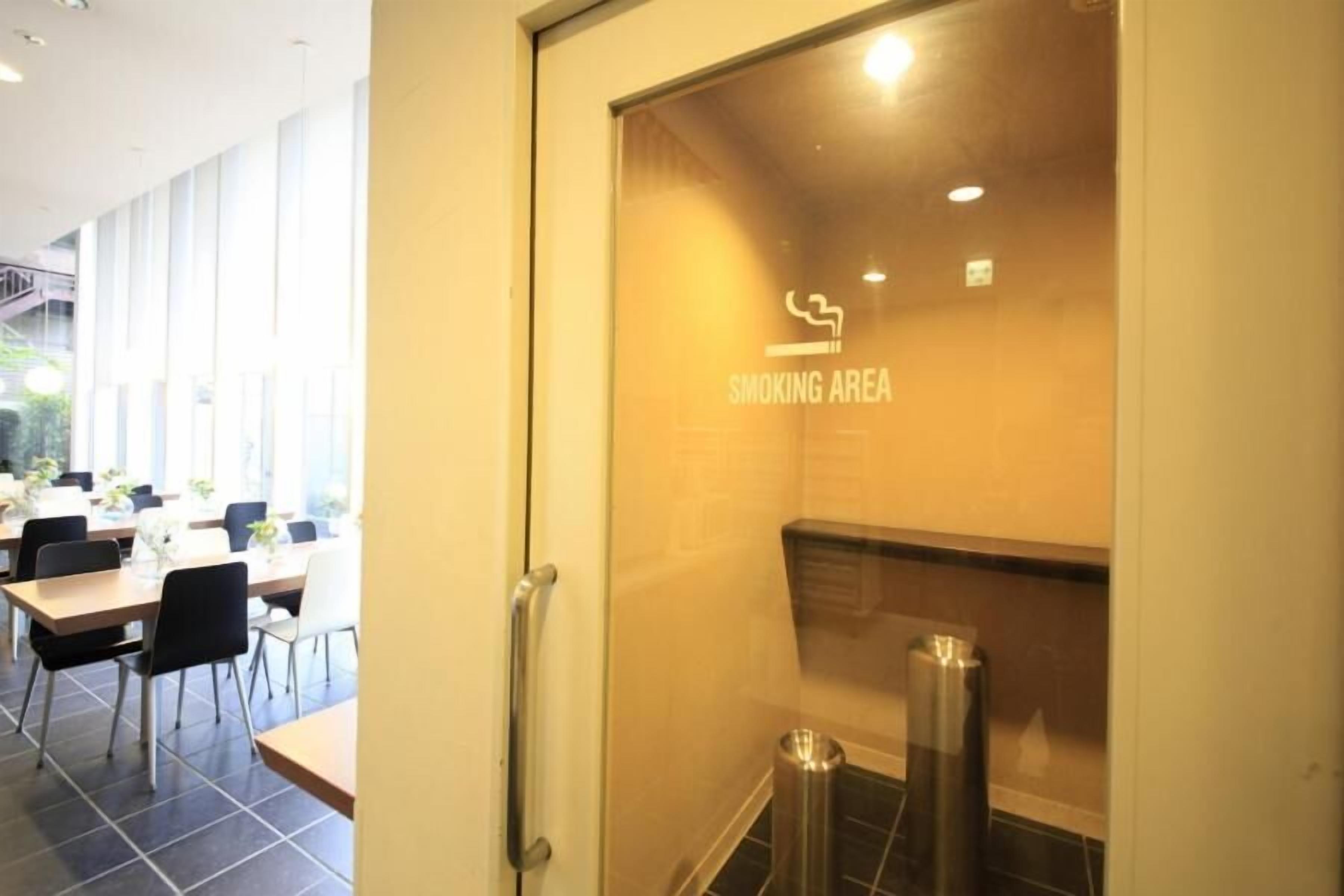 A restaurant with a glass door marked "SMOKING AREA" and a view of the dining area with tables and chairs.