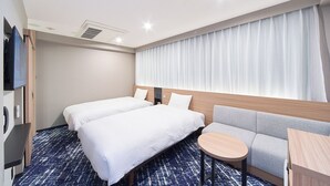 Quarto de hotel com duas camas, um sofá, uma mesa pequena e uma televisão.