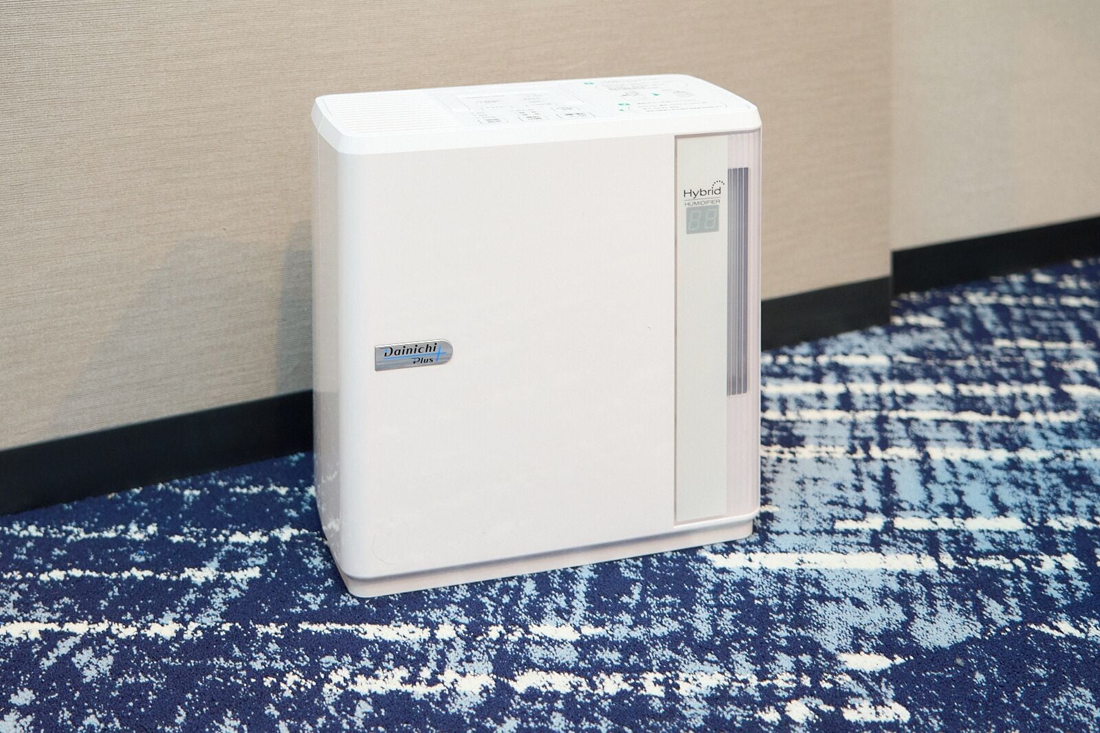 Un humidificador Dainichi Plus blanco con pantalla digital sobre una alfombra de diseño azul y blanco.