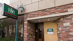Um edifício com fachada de tijolos e uma placa verde com a inscrição 'R&B'.