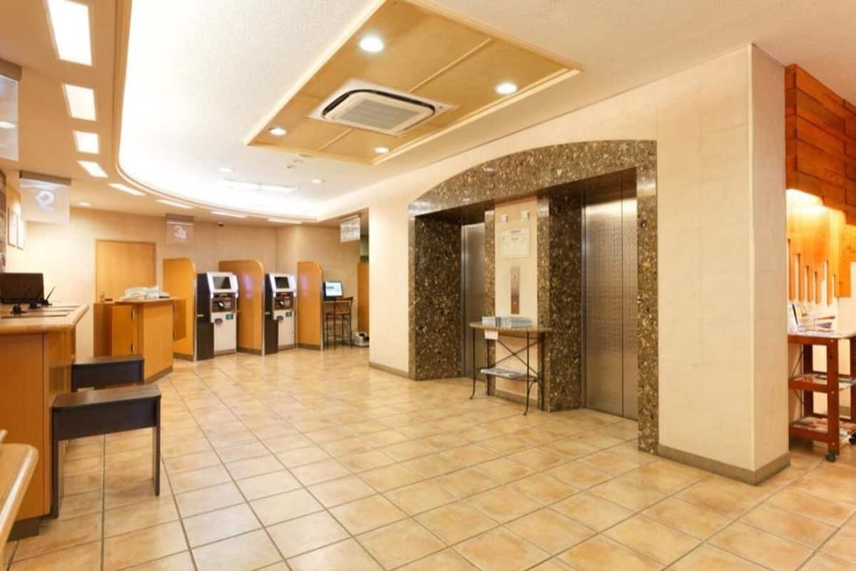 A hotel lobby with a reception desk, seating area, and an elevator.