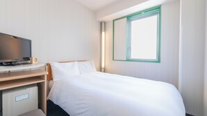 A hotel room with a bed, a desk with a television, a small refrigerator, and a window with a green frame. - Washington R&B Hotel Hakata Ekimae Dai 1 (Fukuoka)