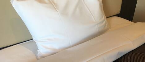 Un almohadón blanco sobre una cama con funda de almohada a rayas.