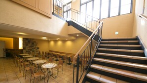 A multi-level indoor space with a staircase, multiple tables, and chairs arranged on the ground floor. - R&B Hotel Kobe Motomachi (Kobe)