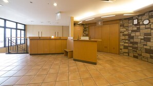 A reception area with a wooden counter, a stone wall with a clock, and a staircase to the left. - R&B Hotel Kobe Motomachi (Kobe)