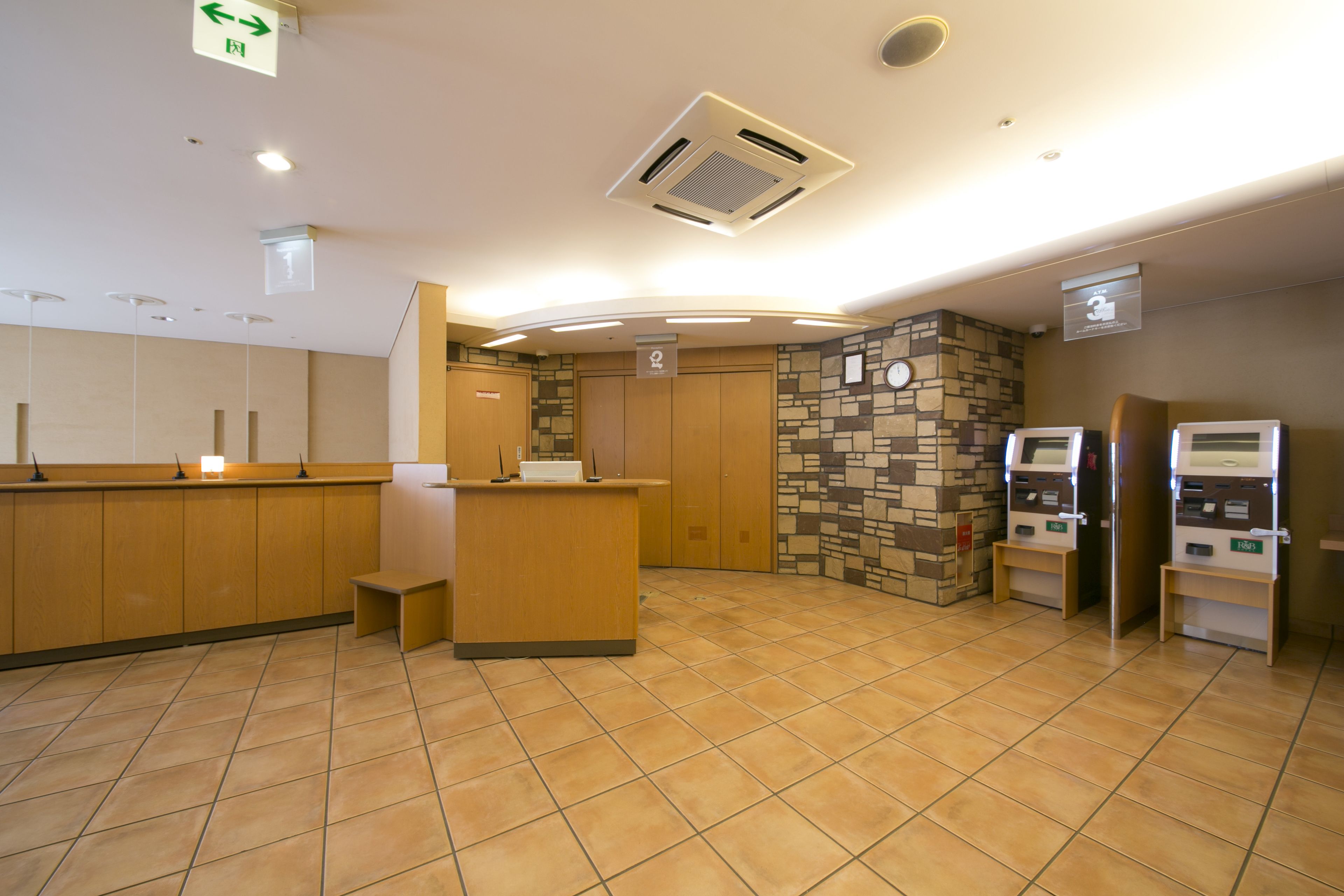 A reception area with a wooden counter, a stone wall, and a self-service kiosk.