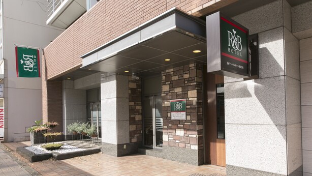 The exterior of R&B Hotel with a stone facade, a covered entrance, and a signboard. - R&B Hotel Kobe Motomachi (Kobe)