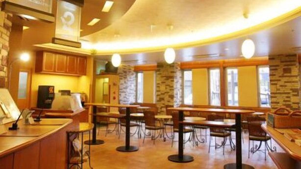 Un restaurante con mesas y sillas de madera, pared de piedra y un cartel con el número 1.