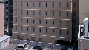 Un hotel de varios pisos con un llamativo letrero de R&B en el techo, que presenta una fachada uniforme con ventanas regularmente espaciadas.