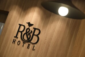 Een houten wand met het logo van R&B Hotel.