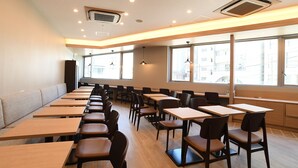 Un aula moderna con filas de escritorios y sillas, ventanas amplias y rejillas en el techo.