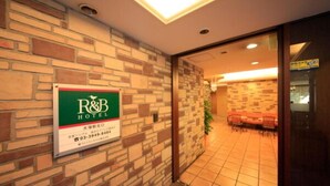 Zona de recepción de un hotel con una pared de piedra y un cartel de R&B Hotel.