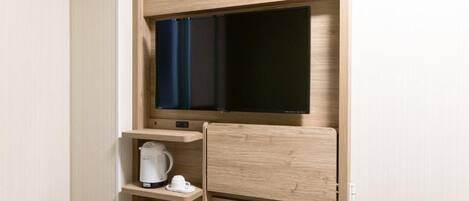 A compact room with a built-in TV, a coffee maker, and a small cabinet.