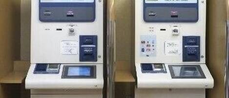 Two identical self-service kiosks with digital displays, card slots, and a cash drawer.