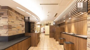 A hotel reception area with a stone wall, wooden reception desks, and a tiled floor. - Washington R&B Hotel Higashinihombashi (Tokyo)
