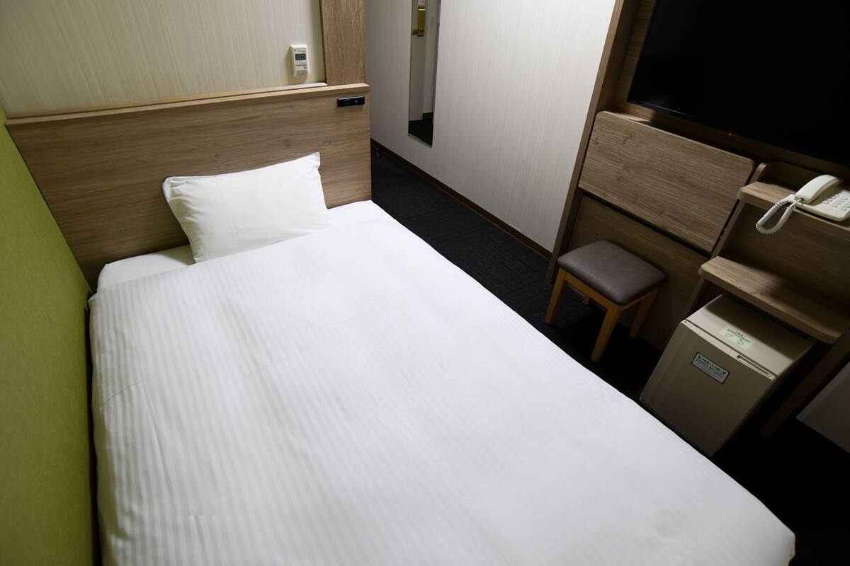 Ein Hotelzimmer mit Bett, Schreibtisch, Stuhl, Fernseher und Minibar.