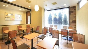 A restaurant with tables and chairs, a large window with a view, and a wall with a poster. - Washington R&B Hotel Higashinihombashi (Tokyo)
