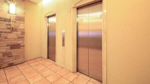 An elevator area with a stone wall and tiled floor. - Washington R&B Hotel Higashinihombashi (Tokyo)