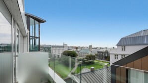 Un bâtiment moderne doté d’un balcon en verre qui offre une vue sur le paysage urbain.
