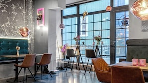 Un espace repas moderne avec un banc capitonné de couleur turquoise, plusieurs chaises et une grande fenêtre offrant une vue dégagée.